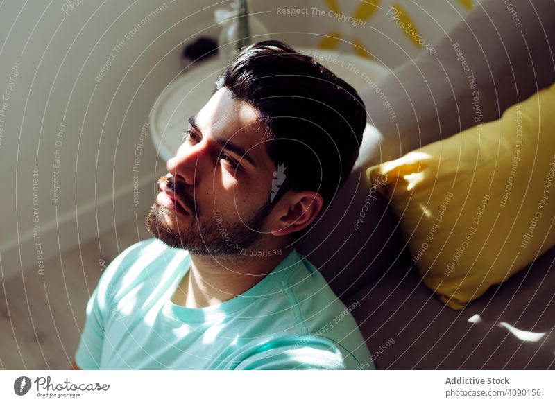 Young sad man sitting on couch at home lonely tired expression sofa young male depressed stressed weary alone serious handsome successful cool stylish hairstyle