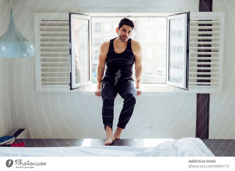 Young happy man sitting on window freedom books bed young male joy cheerful handsome successful elegant cool stylish hairstyle beard mustache casual sleeveless