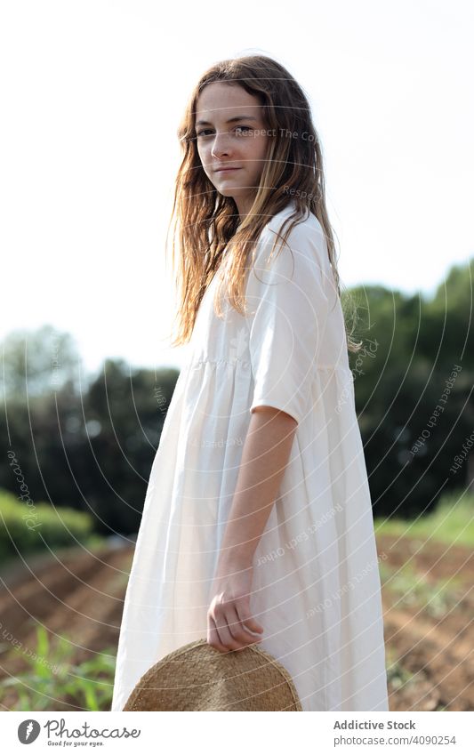 Portrait of teenager on farm field portrait hat confident standing sprouts summer nature sunny daytime catalonia spain anoia girl young rural rustic agriculture