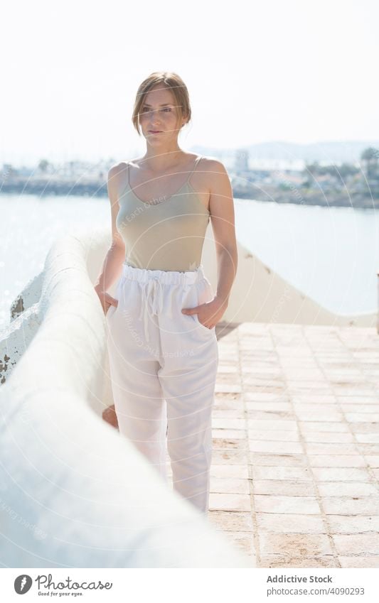 Sensual woman walking on embankment sea sensual dreamy sunny daytime female railing border thoughtful lifestyle leisure rest relax young city lady pavement