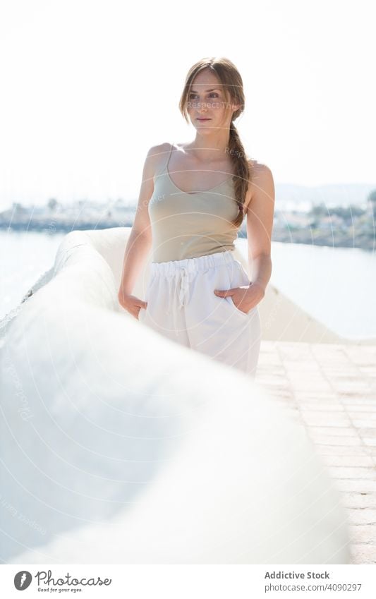 Sensual woman walking on embankment sea sensual dreamy sunny daytime female railing border thoughtful lifestyle leisure rest relax young city lady pavement