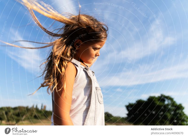 young girl posing in sunlight looking away confident summer nature stylish thoughtful child adorable expression vacation innocent childhood trendy style