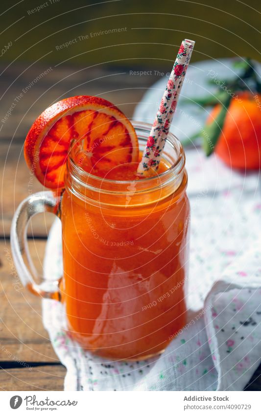 Citrus juice with blood orange citrus jar straws napkin table fresh drink healthy beverage refreshment sweet ripe slice piece mug fabric cloth wooden lumber