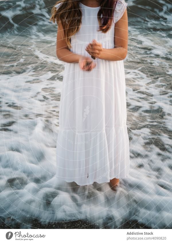 crop girl standing on seaside among waves portrait charming water beach adorable summer beautiful female kid child childhood preschooler innocence serene