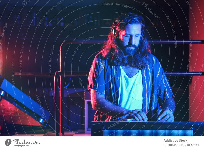 Bearded Dj man playing disco music in a club electronics discotheque crowd volume professional audio show mixer stereo sounds part headphone panel instrument dj