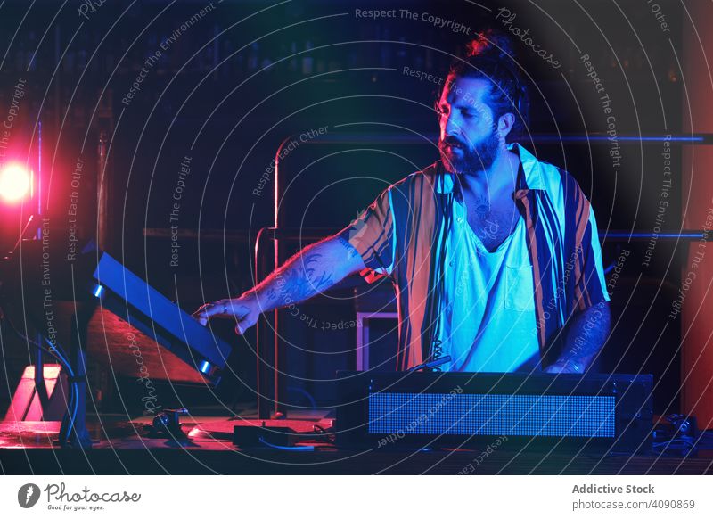 Bearded Dj man playing disco music in a club electronics discotheque crowd volume professional audio show mixer stereo sounds part headphone panel instrument dj