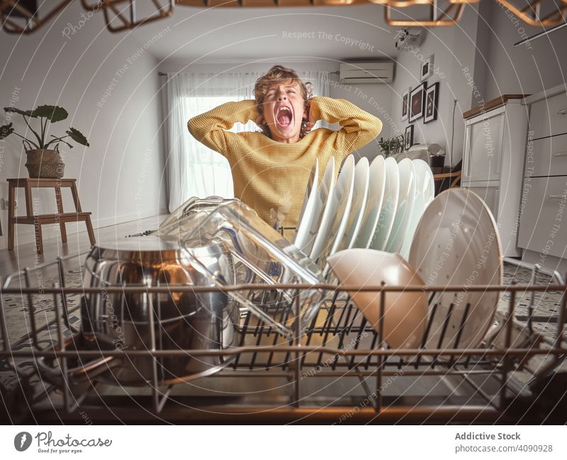 Boy yawning near open dishwasher boy kitchen hate routine housework dishware home closed eyes kid child wavy hair pajamas kitchenware technology equipment cozy