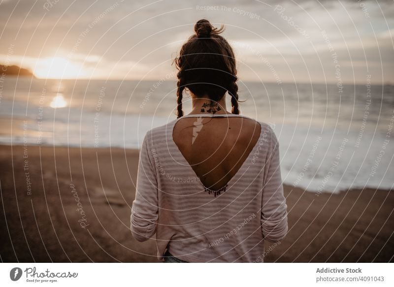 Anonymous female standing towards waving sea on sunset woman beach waves evening young summer vacation ocean water storm nature countryside travel trip tourism