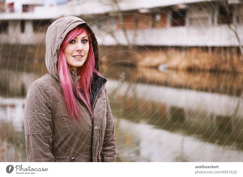 young woman with pink hair, piercings and tattoos in front of graffiti covered houses Young woman Piercing Tattoo real people Subculture pierced Tattooed