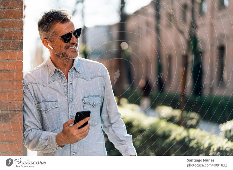 Business man listening to music in the street. person lifestyle people middle aged handsome senior outdoors caucasian city adult male portrait casual urban