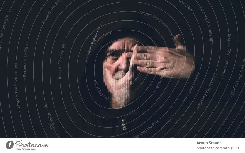 portrait of a man with a hoodie holding a hand in front of his face beard double exposure stripes hands eye mouth silent blind studio black indoor blurred