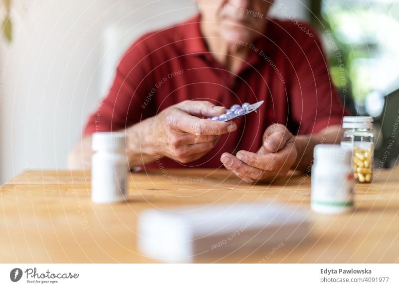 Senior man taking prescription medicine at home senior elderly grandfather old pensioner retired retirement aged mature house male people lifestyle