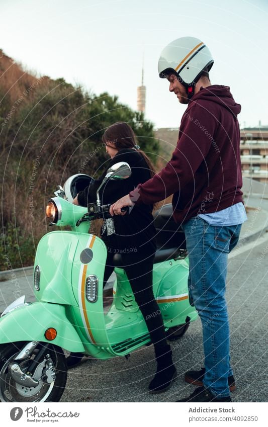 Man helping woman sit to bike helmet friendship scooter activity leisure street adventure motorcycle travel enjoying transportation motorbike young lifestyle