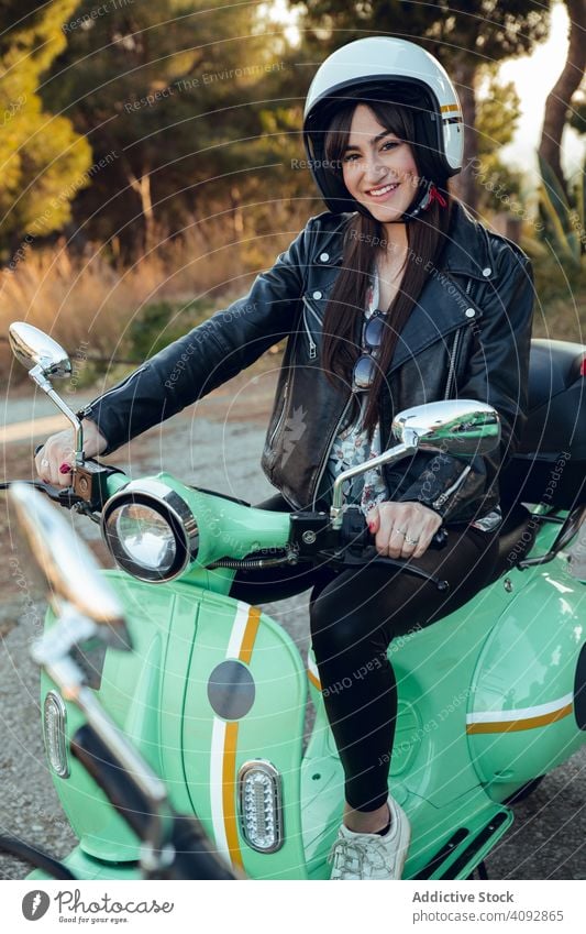 Woman in motorcycle helmets sitting on bike and looking at camera woman attractive scooter activity leisure street cheerful adventure travel enjoying female