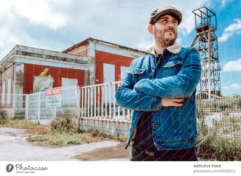 Overweight guy outside industrial building man looking away overweight exterior thoughtful casual cap male derelict grungy rough weathered sky clouds pensive