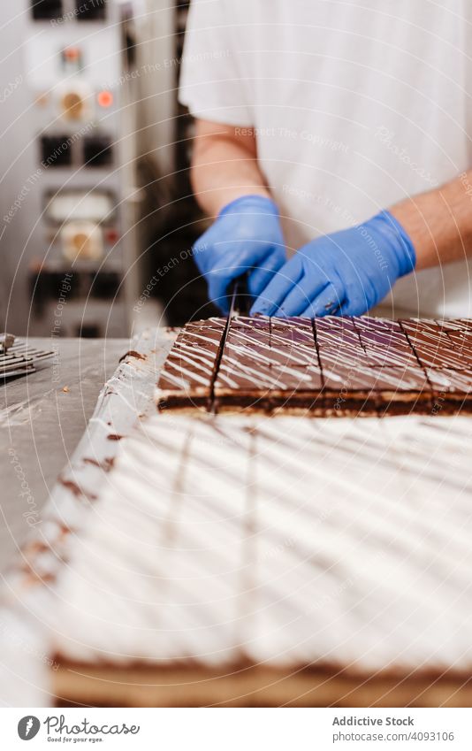 Anonymous cook cutting cake on table confectioner bakery knife pastry sweet fresh kitchen food preparation small business man uniform glove quality dessert