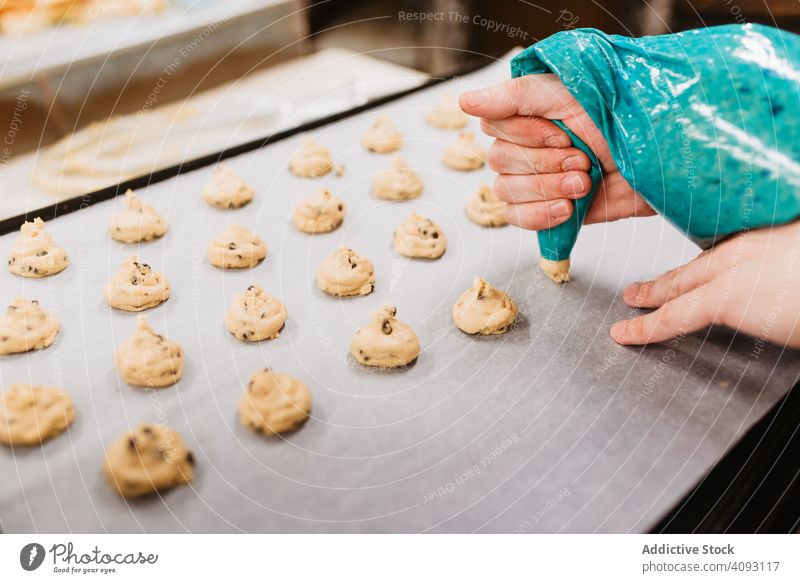 Crop baker squeezing dough on tray confectioner bakery squeeze cookie work kitchen preparation professional cuisine food paper pastry restaurant sweet chef