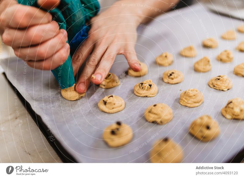 Crop baker squeezing dough on tray confectioner bakery squeeze cookie work kitchen preparation professional cuisine food paper pastry restaurant sweet chef