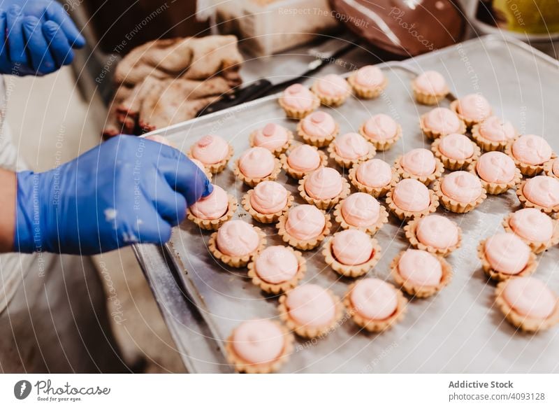 Anonymous baker decorating small cakes confectioner bakery pastry work quality food traditional man preparation production small business occupation patisserie