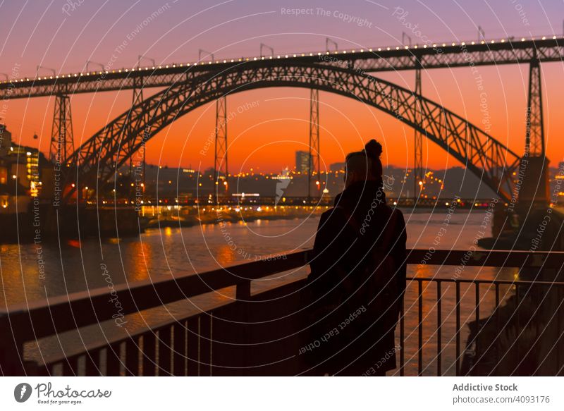 Female walking on embankment during sundown tourist city sunset bridge river border woman water architecture landmark sky cloudless female evening dusk twilight