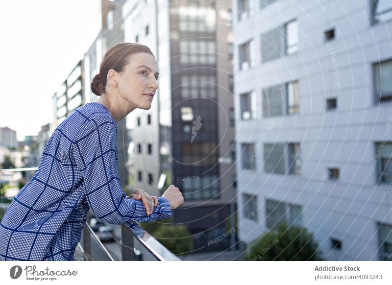 Smiling businesswoman standing on balcony office smile city sunny daytime break rest young female professional relax railing cheerful joy entrepreneur lady