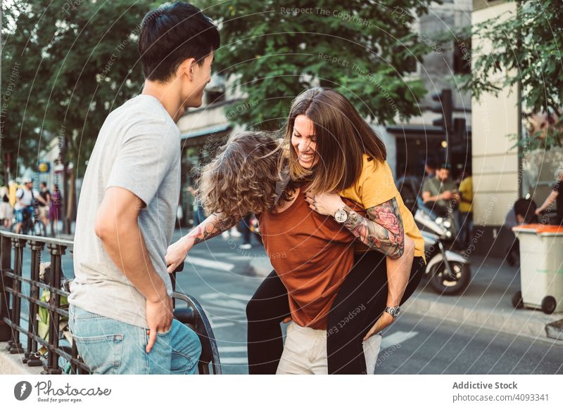 Carefree multiracial friends having fun on street piggyback playful carefree laugh stand city together summer diverse bonding happy friendship urban people