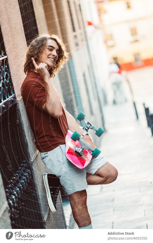 Man carrying longboard on the street man modern urban city stand hold sportive young adult fit strong extreme arm exercise lifestyle skater active fun skating