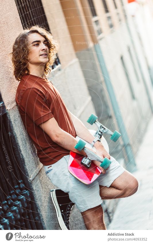 Man carrying longboard on the street man modern urban city stand hold sportive young adult fit strong extreme arm exercise lifestyle skater active fun skating