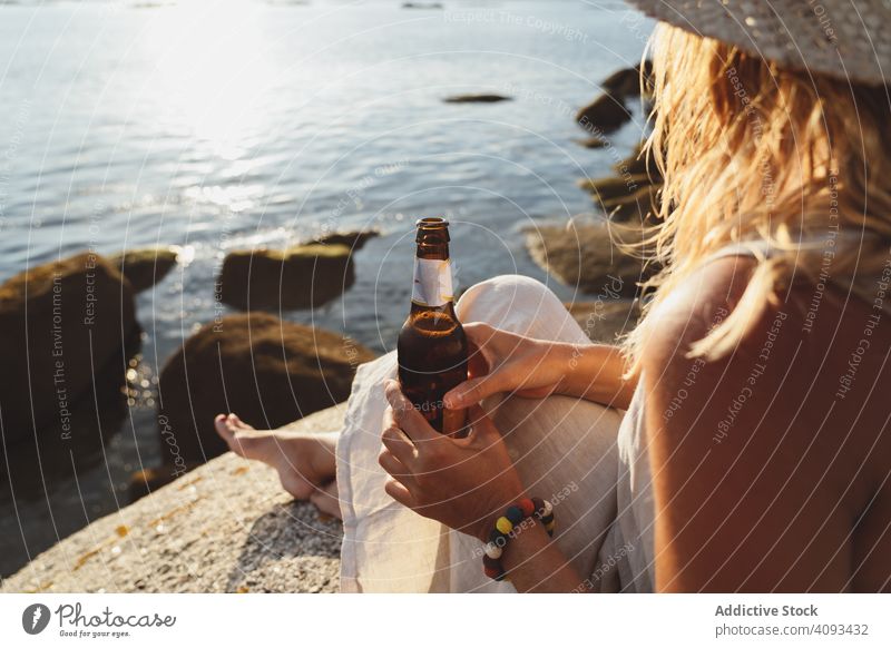 Woman relaxing and drinking beer at beach woman coast seaside lounge refreshment chill sunlight enjoy solitude bottle travel alcohol holidays trip vacation