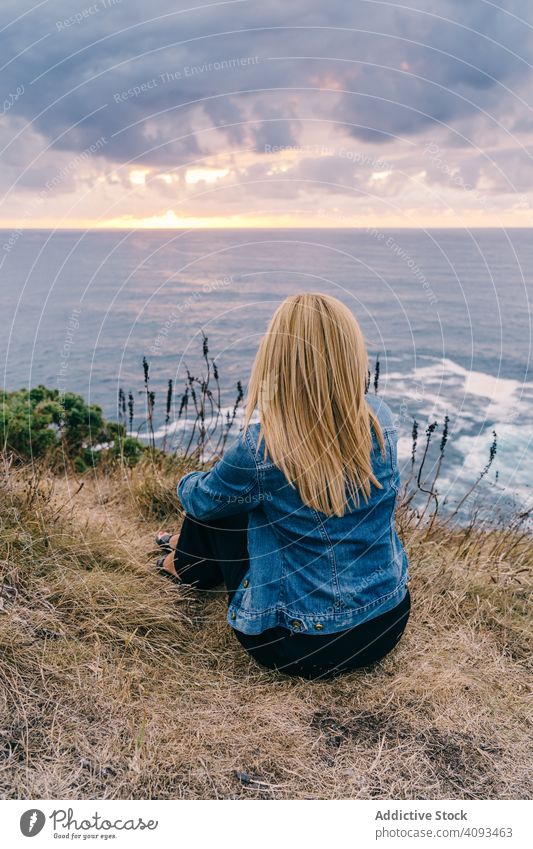 Woman on seashore against dusky clouds woman horizon seascape sunset harmony contemplation overcast chill scenic trip travel ocean tranquil recreation twilight