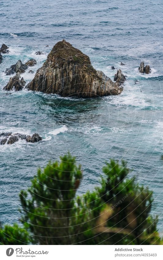 Rocky peaks surrounded by foamy water in windy day ocean scenic cloud nature landscape nautical dramatic rocky sea coast travel tourism natural dangerous