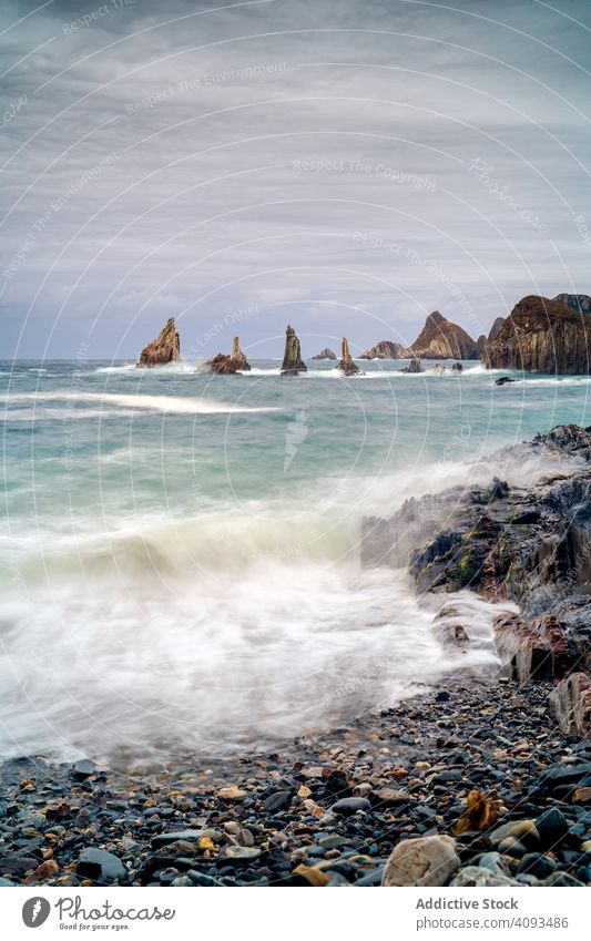 Rocky peaks protrude from water in cloudy day seashore ocean coastline bay scenic nature landscape nautical dramatic rocky travel tourism natural dangerous