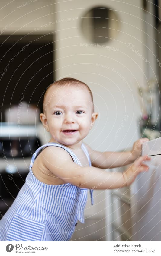 Happy baby sitting on floor in kitchen happy home cozy counter parquet fun child toddler childhood kid barefoot excited innocence rest relax wooden lumber