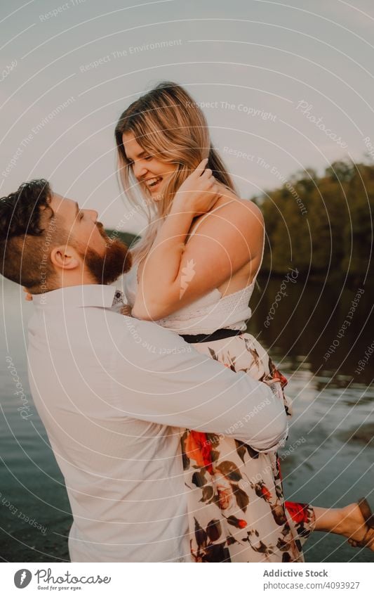 Loving man carrying happy woman on hands on shore couple lake hug love carrying on hands affection romance relationship nature summer gentle passion romantic