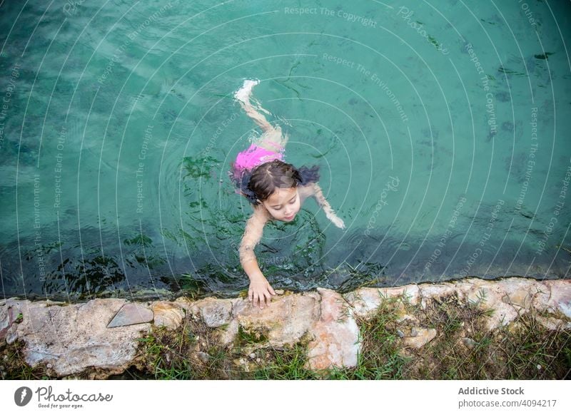 Girl swimming in pool in outdoor spa girl water border fun little stone poolside kid child joy wet resort relax rest warm autumn fall season pond childhood