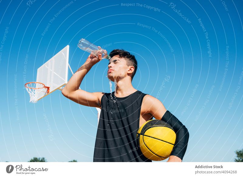 Young man standing with ball and playing on basketball court outdoor. athlete competition sports equipment adult recreation action portrait active activity