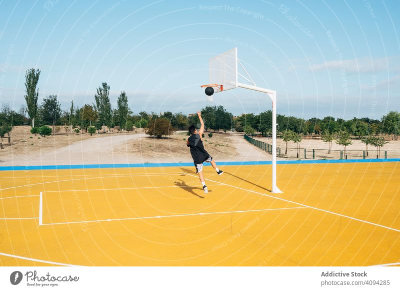 Young man playing on yellow basketball court outdoor. athlete competition sports equipment adult recreation action portrait active activity asphalt athletic