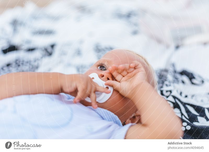 Blonde baby with sleepy expression dream pacifier human body blonde infant newborn clothes bed boy lovely bedroom bored innocent hand person tired blanket