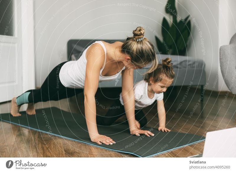 A young sports mom and a girl together do exercises at home. Healthy development of parents and children, healthy lifestyle woman fitness mat beautiful little