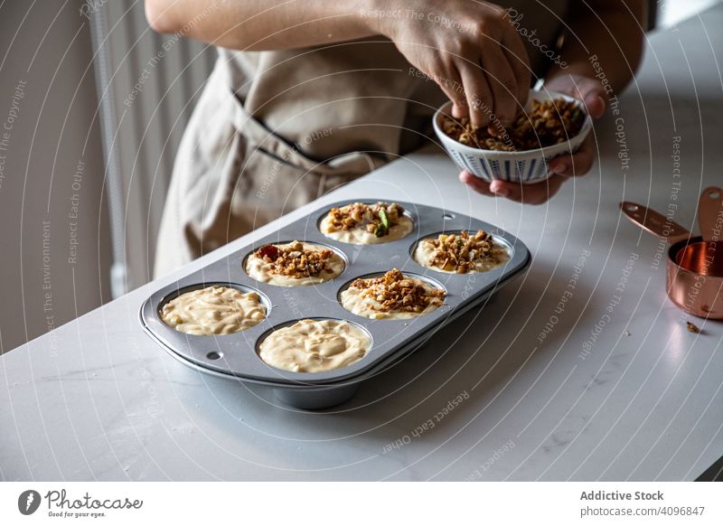 Faceless person cooking muffins with walnuts baker sprinkle homemade preparation dough cupcake baking dish delicious dessert food crushed tasty pastry raw