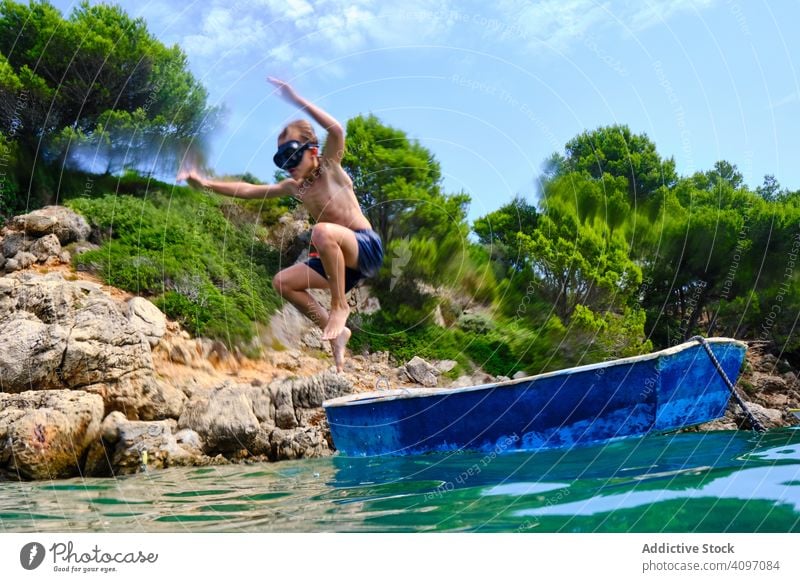 Sporty boy jumping in sea child holiday dive coast boat summer active water sporty energy sail cliff seashore rocky mask travel sunny tree nature kid wet