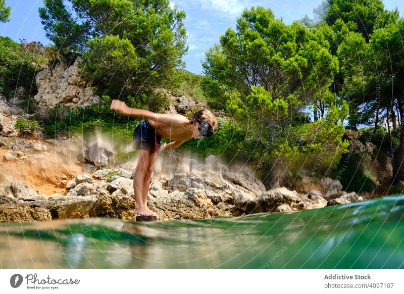 Little boy getting ready to jump in water sea dive summer seashore balance child mask coast travel active rocky tourism cliff sporty recreation wet energy