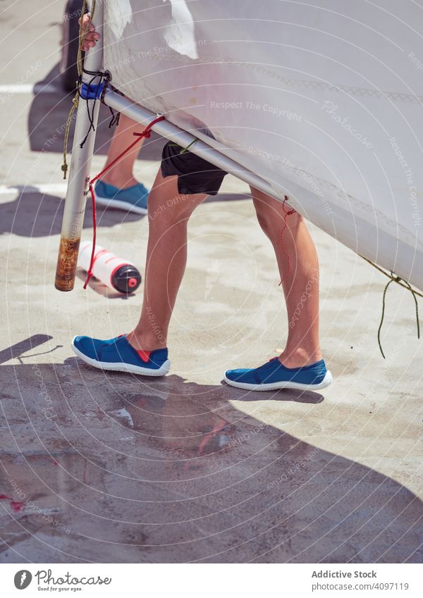 Skilled boy in blue life jacket carrying white sail walking yacht kid cruising water shore sport wind ocean holiday tense swimming childhood hobby fun wet