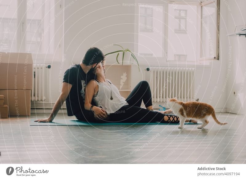 Loving couple cuddling on floor while cat walking around cuddle loving embrace tender sit ginger hipster modern minimalistic moving home relocation apartment