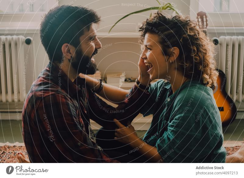 Loving couple embracing while sitting on apartment floor embrace loving cuddling tender casual smile carpet home love together happy hug romantic relationship