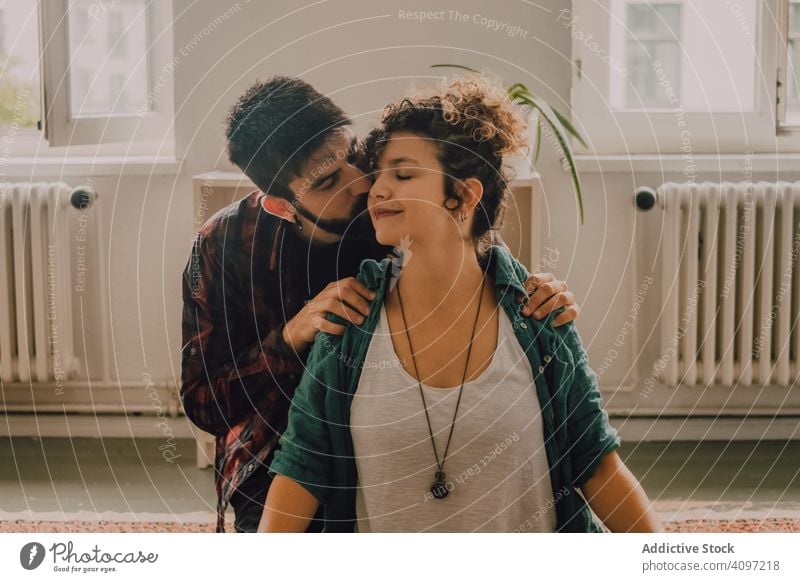 Man rubbing shoulders of joyful woman resting on floor at home couple massage stretch help relaxed sit lotus position boyfriend girlfriend casual hipster happy