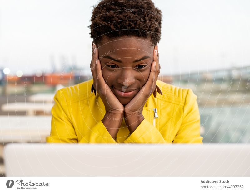 Female working on laptop at table woman using desk city african american jacket yellow female wooden young casual workplace busy remote freelance surfing