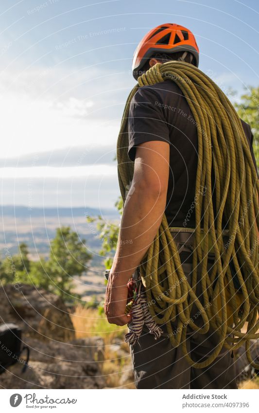 A climber is preparing his ropes to start climbing sport mountaineering man adrenaline aspiration difficult strength strong athletic person active sky adventure