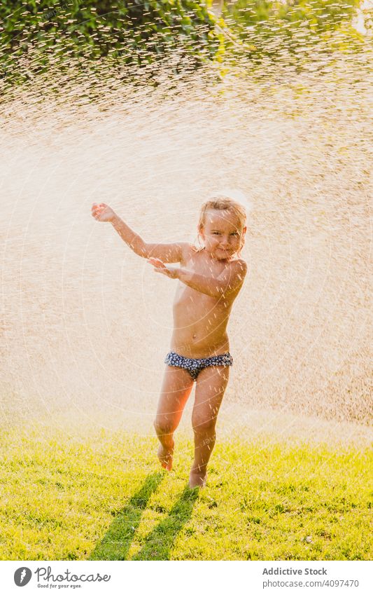 Shirtless girl under spraying water in garden play lawn summer sunny daytime fun child kid little panties shirtless childhood happy joy yard wet drop stream