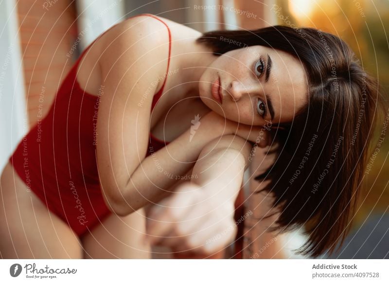 Gorgeous female in red swimsuit on balcony woman gorgeous sensual seductive glamorous fashionable vogue model attractive serious pensive thoughtful chic pretty